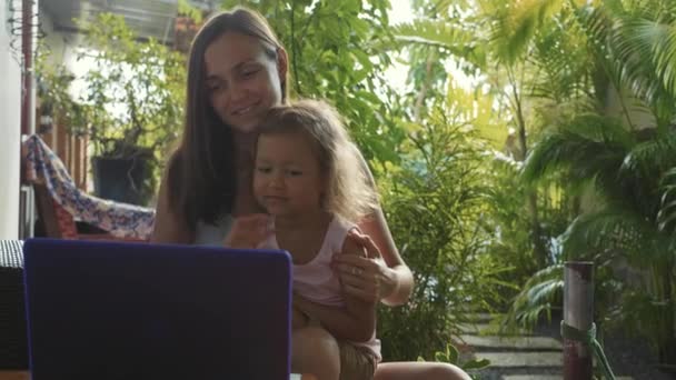 Junge Frau mit kleiner süßer Tochter benutzt gemeinsam Laptop in Zeitlupe — Stockvideo