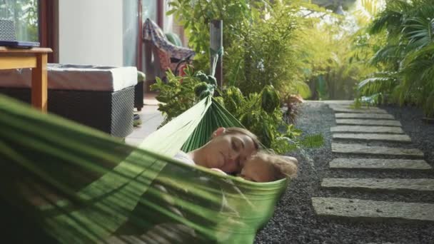 Lycklig mor och dotter avkopplande tillsammans i en hängmatta i trädgården i sommardag — Stockvideo