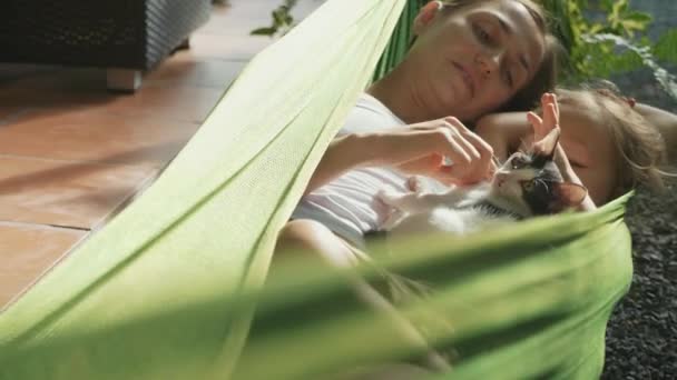 Happy mother and daughter relaxing together in a hammock at garden in summer day — Stock Video