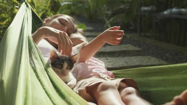 Feliz madre e hija relajándose juntas en una hamaca en el jardín en el día de verano — Vídeos de Stock