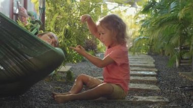 Hamakta yatan ve küçük kızıyla birlikte oynayan genç anne