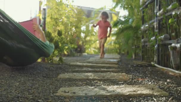 Niña caminando por el camino en el jardín. Primer plano pies se acercan a la cámara . — Vídeos de Stock