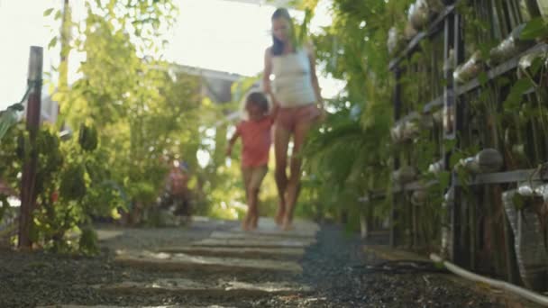 Mother with little girl walking on path in garden. Feet come near to camera. — Stock Video