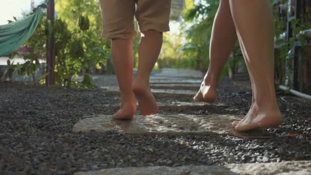 Mère avec petite fille marchant sur le chemin dans le jardin. Pieds reculer de la caméra . — Video