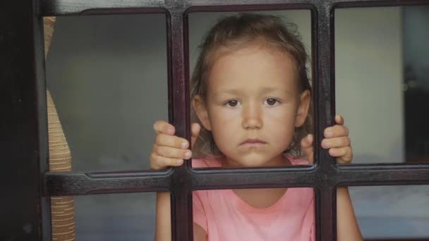 Retrato niña mirando por la ventana, desde fuera disparado en cámara lenta — Vídeos de Stock