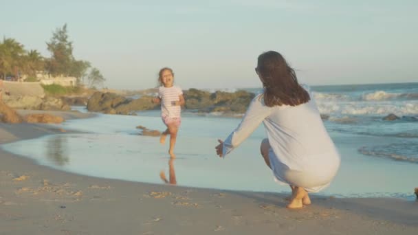 Mãe com bebê se divertindo na costa do mar em câmera lenta . — Vídeo de Stock