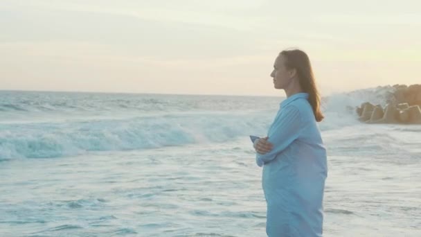 Giovane donna in piedi sulla spiaggia e guardando un mare al rallentatore — Video Stock