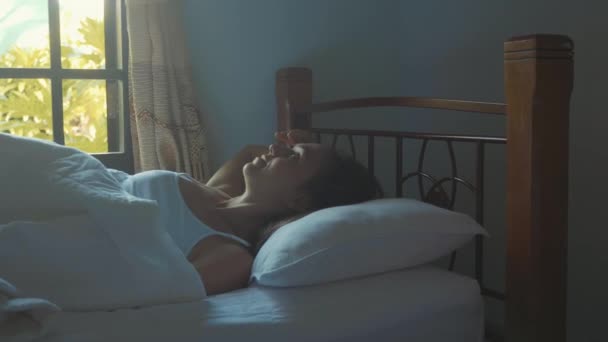 Портрет просто прокинулася молода жінка лежить в ліжку вдома вранці . — стокове відео