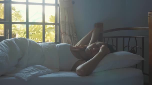 Молодая женщина спит в постели дома и медленно просыпается утром . — стоковое видео