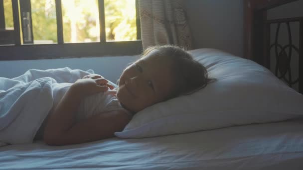 Portret van net wakker kind meisje liggend in bed thuis op ochtend. — Stockvideo