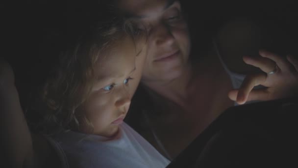 Προσωπογραφία της μητέρας με μικρή κόρη χρησιμοποιώντας tablet στο κρεβάτι τη νύχτα στο σπίτι. — Αρχείο Βίντεο