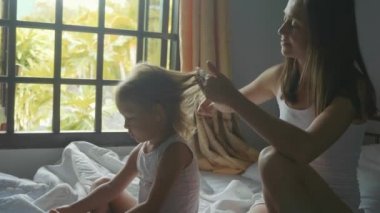 Genç anne yatakta ve kızı yavaş çekimde penye oturur.