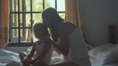 Genç anne yatakta ve kızı yavaş çekimde penye oturur.