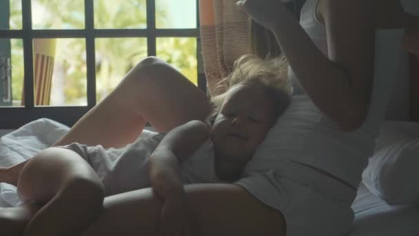 Feliz hija se acuesta en sus madres regazo mientras ella acaricia su cabello, cámara lenta . — Vídeos de Stock