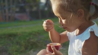 Sevimli küçük kız bir passionfruit ağır çekimde açık yemek Close-Up