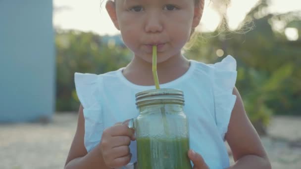 Portrait of cute little girl drinks a smoothies outdoor in slow motion — Stock Video