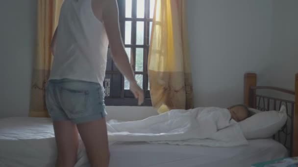 El niño duerme en el cuarto oscuro. Madre viene, abre las cortinas y la despierta . — Vídeo de stock