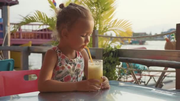 Grappig meisje is zitten in een rivier cafe aan een tafel en het drinken van SAP — Stockvideo