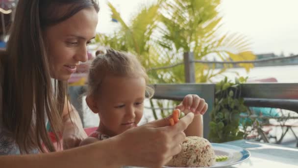 若い母親を箸で食べるかわいい小さな娘を教えてください。 — ストック動画