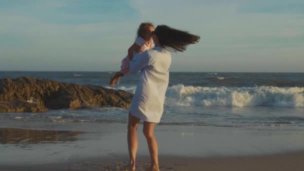 Mor spinning hennes lilla dotter på sandstranden varm solnedgång belysning. — Stockvideo