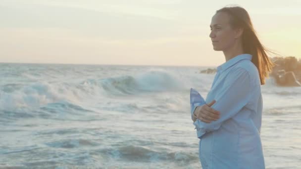 Porträt einer jungen Frau, die im warmen Licht des Sonnenuntergangs auf das Meer blickt — Stockvideo