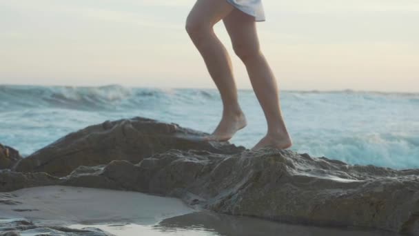 Piedi femminili nudi che camminano sulla spiaggia rocciosa. Gambe che passano la pietra sulla riva se . — Video Stock