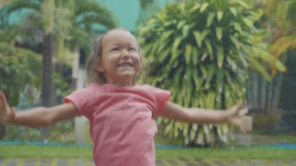 Портрет 5-летняя девочка развлекается во время тропического дождя, замедленная съемка — стоковое видео