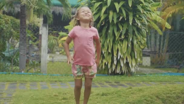 Портрет 5-летняя девочка развлекается во время тропического дождя, замедленная съемка — стоковое видео