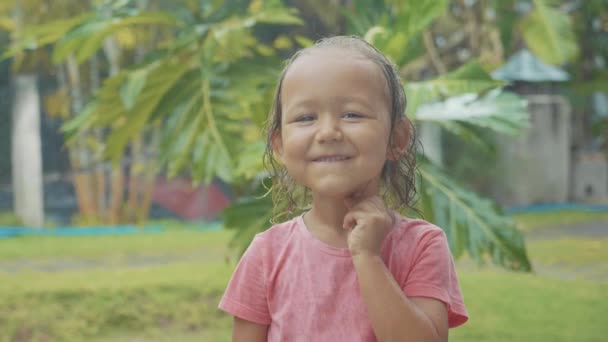 Retrato niña de 5 años mirando a la cámara durante una lluvia tropical — Vídeos de Stock