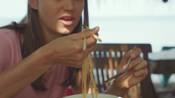 Мать и дочь едят суп с лапшой через палочки для еды в кафе на открытом воздухе — стоковое видео