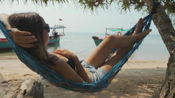 Young happy woman lying on hammock at the sandy beach in slow motion — Stock Video