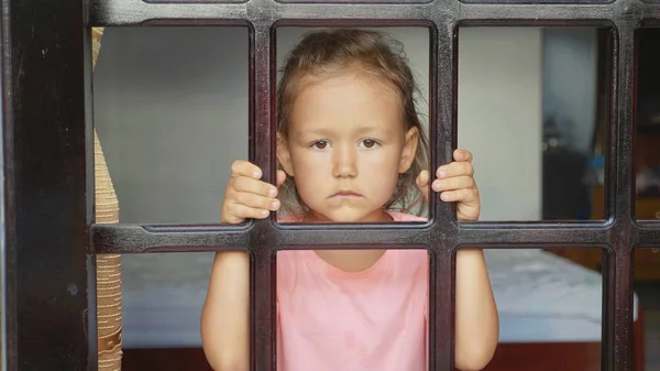 Портрет маленькой девочки, смотрящей в окно, с внешней съемки — стоковое фото