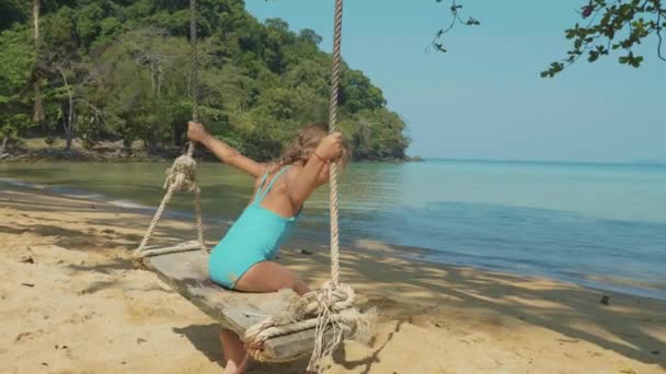 Feliz niña riendo balanceándose en la playa de arena tropical con emociones divertidas — Vídeo de stock