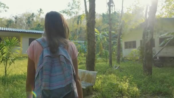 Mujer joven caminando en el camino del campo a través de pueblo asiático, cámara lenta . — Vídeo de stock