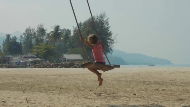 Joyeux rire enfant fille balançant à la plage de sable tropical avec des émotions drôles — Video