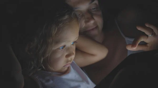 รูปภาพของแม่กับลูกสาว ใช้แท็บเล็ตบนเตียงตอนกลางคืนที่บ้าน . — ภาพถ่ายสต็อก
