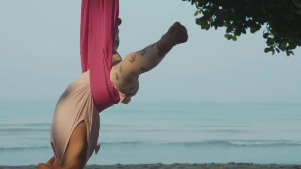 Kleines süßes Mädchen macht Yoga-Übungen mit Hängematte am Strand. — Stockvideo