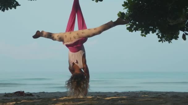 Liten söt barn flicka gör yoga favoritapp med hängmatta på stranden. — Stockvideo