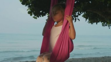Yoga exersice hamak Beach ile yapıyor küçük şirin çocuk kız.