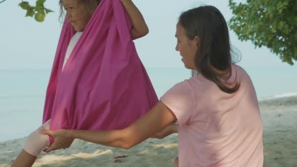 Mother teaching her child girl doing yoga exersice with hammock on the beach. — Stock Video