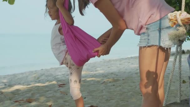Η μητέρα διδάσκει το παιδί κορίτσι κάνει γιόγκα εκγύμνασης με αιώρα στην παραλία. — Αρχείο Βίντεο