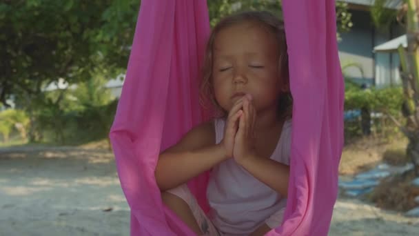 Piccola bambina carina che fa esercizi di yoga con amaca sulla spiaggia . — Video Stock