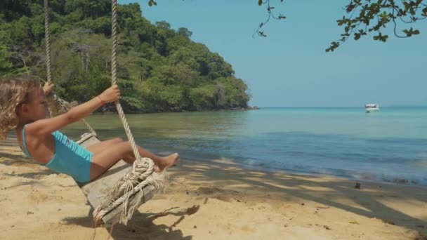 Lyckligt barn flicka gungande på tropisk sandstrand — Stockvideo