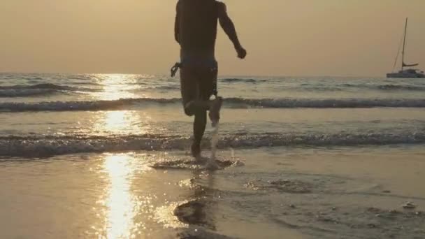 Silueta de niño feliz corriendo hacia el mar en la hermosa luz del atardecer — Vídeos de Stock