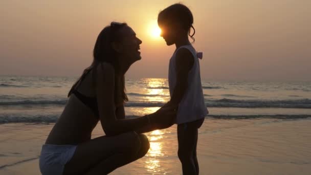 Ласковые чувства матери и маленькой дочери в силуэте на закате — стоковое видео