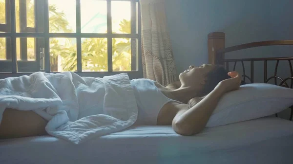 自宅でゆっくりと目を覚ます朝のベッドで寝ている若い女性. — ストック写真