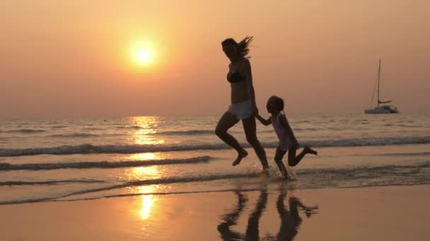 Silhouetteother com pequena filha correndo na costa do mar com as mãos dadas . — Vídeo de Stock