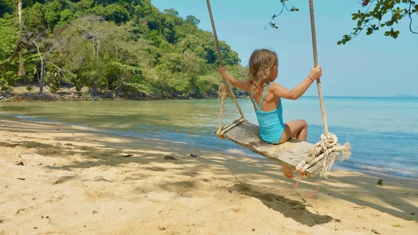 Feliz niña riendo balanceándose en la playa tropical de arena — Foto de Stock