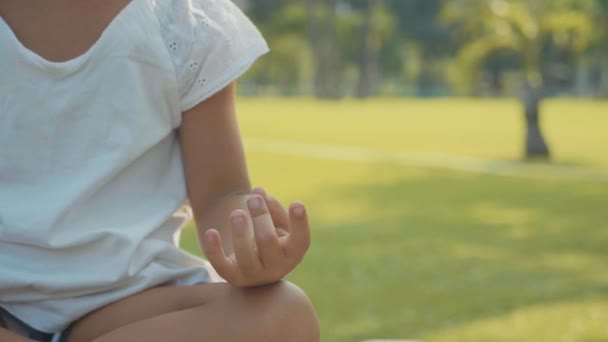 Маленькая девочка медитирует в красивом парке с пальмами на фоне — стоковое видео