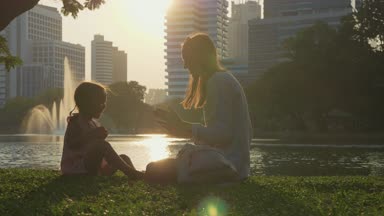 Aile göl ve arka planda gökdelenler ile parkta eğleniyor